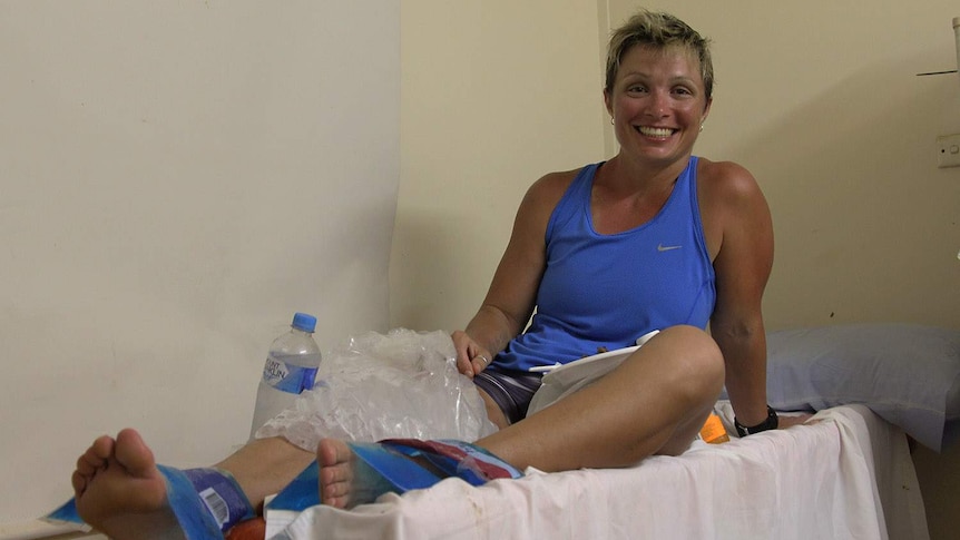 A woman in running clothes lying on a table with ice on her legs