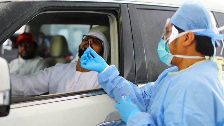 A member of medical staff wearing protective mask and gloves takes a swab from a man during drive-thru coronavirus testing.