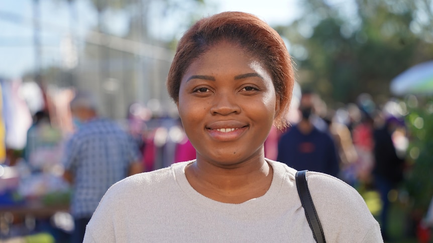 A profile style shot of Adelite Smith smiling at the camera in a market setting