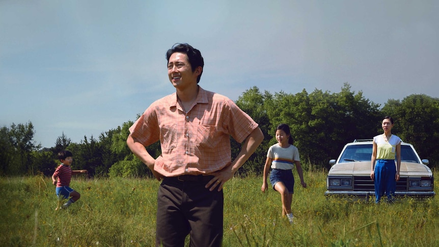 A still from the film Minari with Steven Yeun, patriarch of a family in the foreground, his wife and two kids in the background