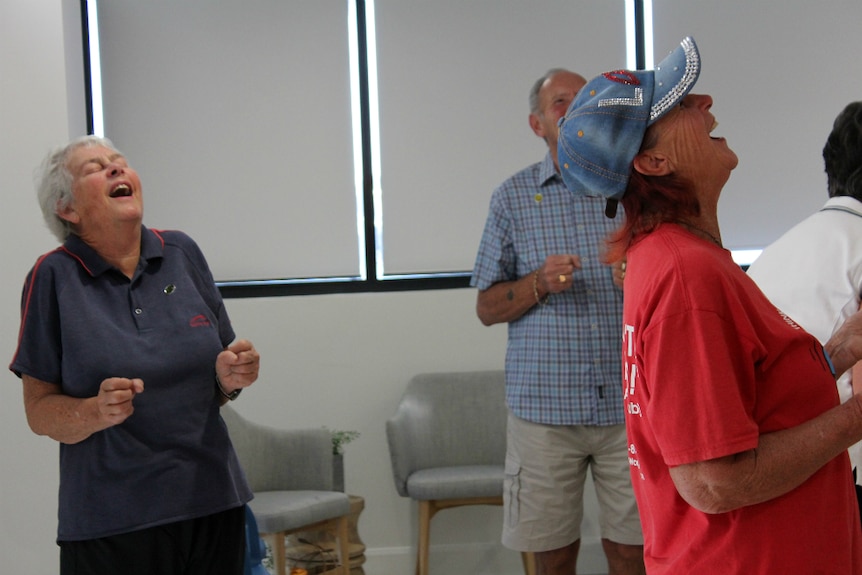 Three adults looking up to the ceiling and laughing.