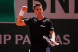 An Australian tennis player clenches his fist in celebration as he shouts with joy after winning a match at the French Open.