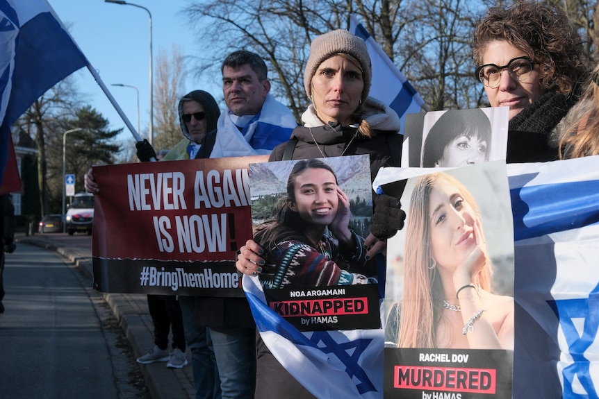 Kobiety niosące izraelskie flagi i zdjęcia młodych ludzi 
