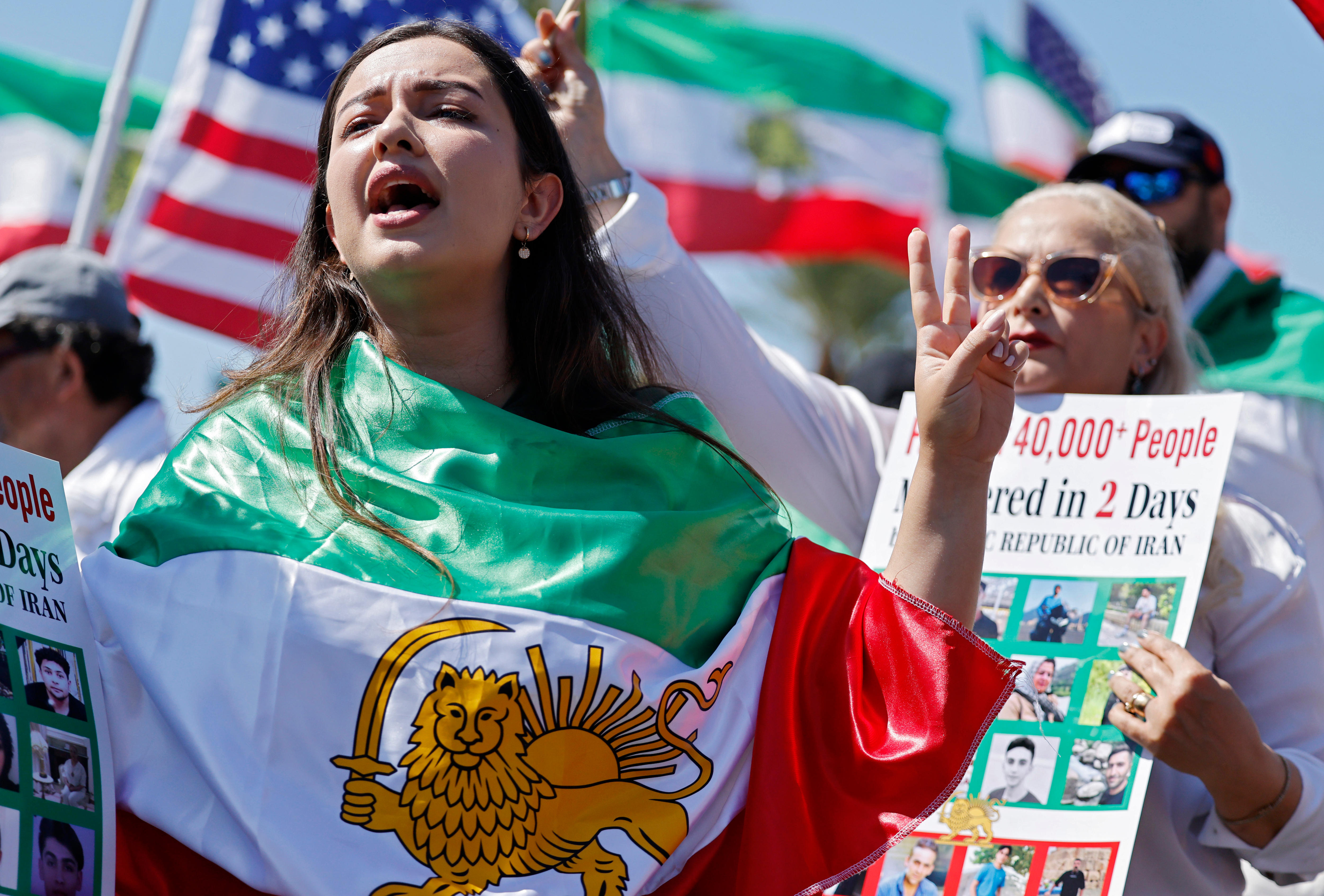 A woman draped in an Iranian 'Lion and Sun' flag yells at a protest