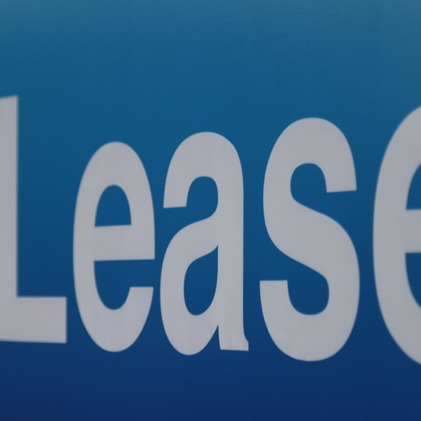 Blue real estate sign with white text reading "lease"