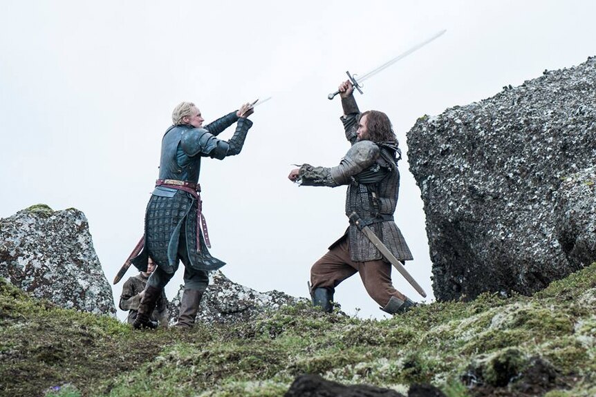 Two male characters swing swords at each other in a scene from Game of Thrones.