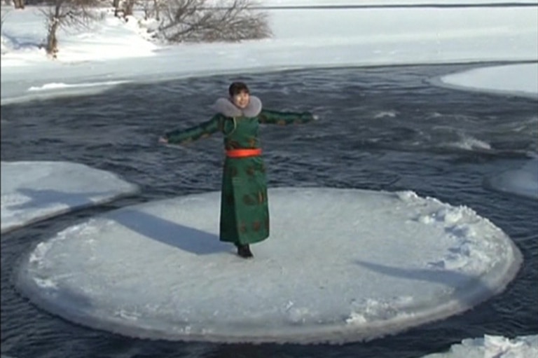 Woman stands on ice disc with arms outstretched.