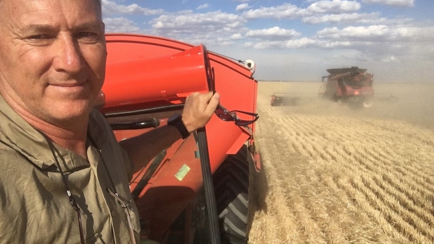 A man takes a selfie on a harvester.