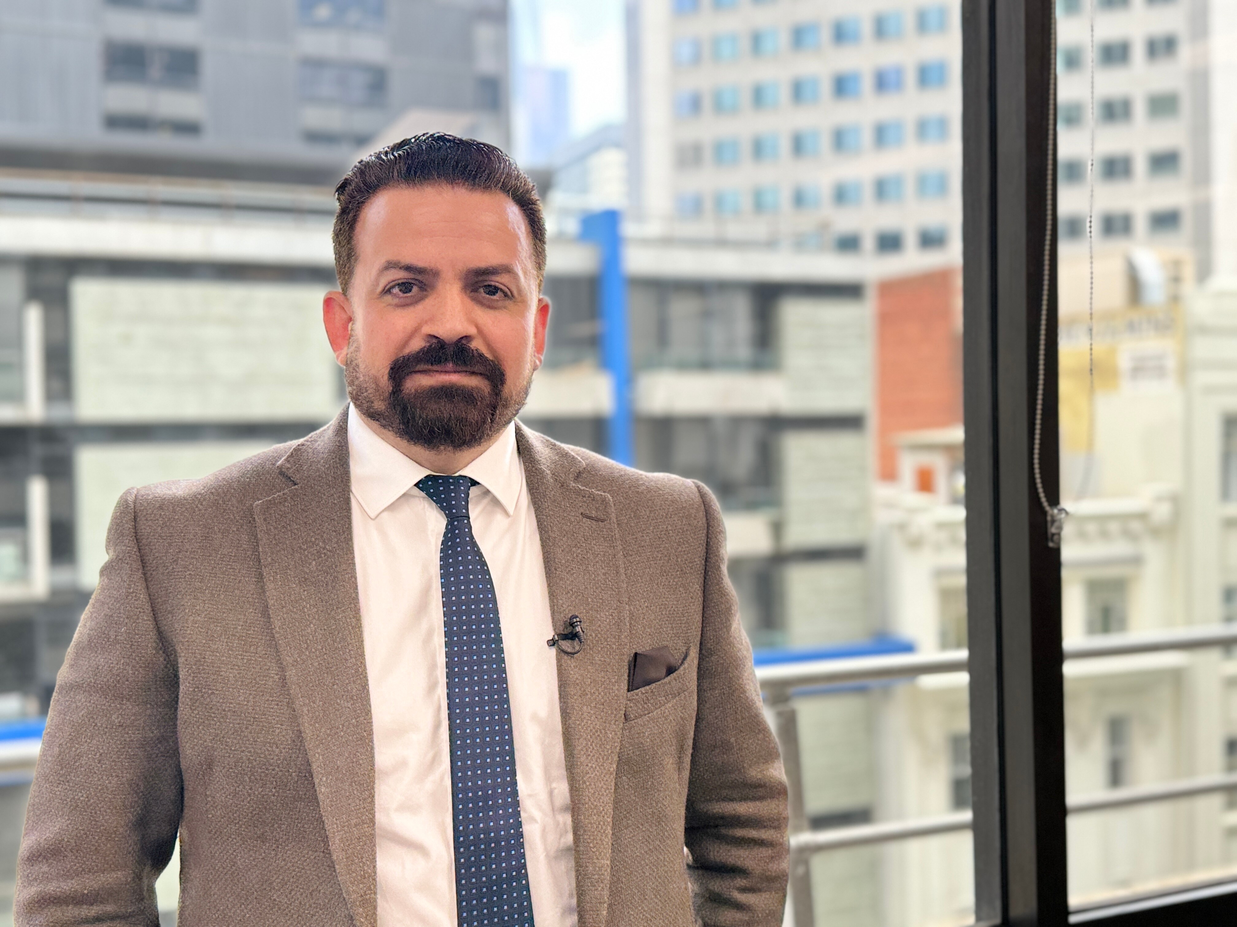 Essam Kotb is a member of Victoria's growing Muslim population, and is pictured standing next to a high-rise window.
