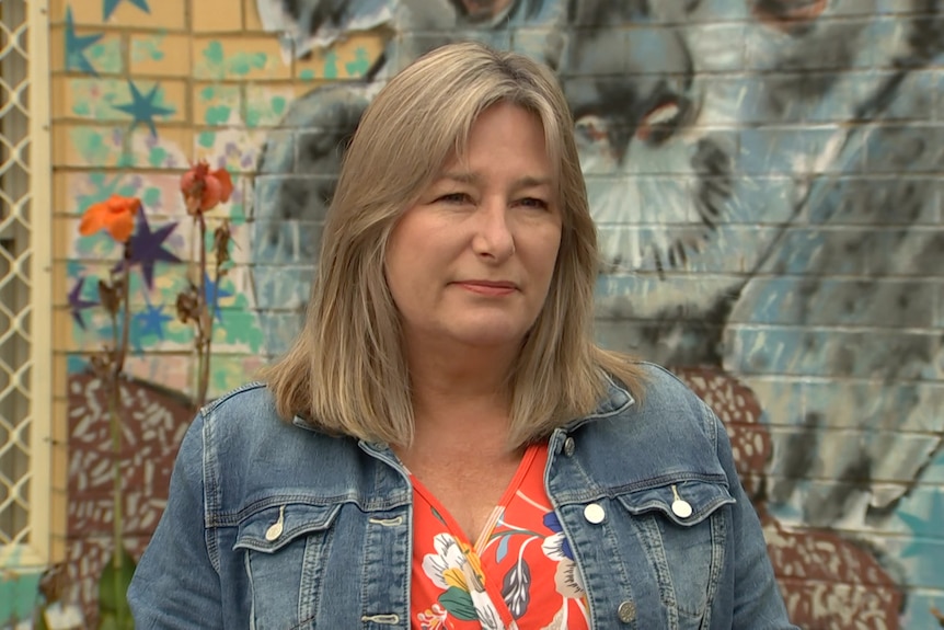 A woman in a denim jacket looks serious.