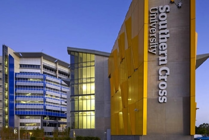 A large building with Southern Cross University written in white letters  on the side of the building at dusk