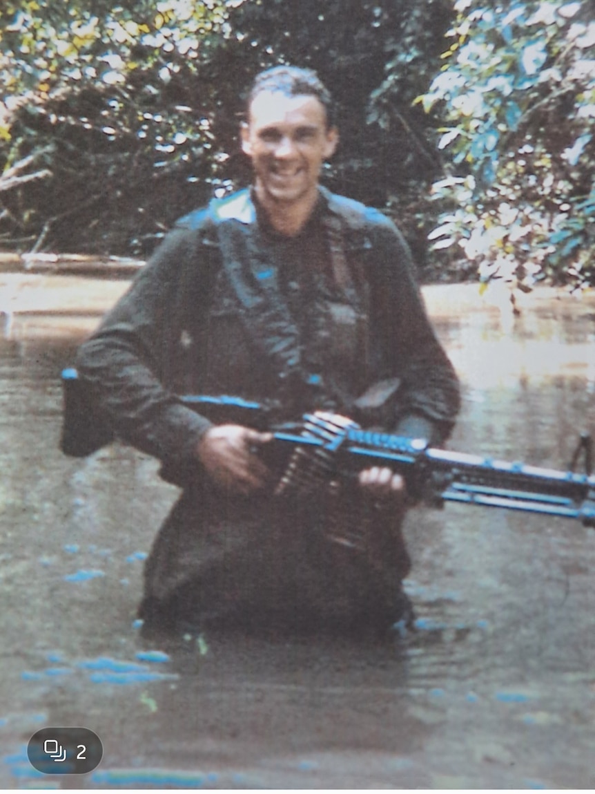 A young army man in his 20s holding a gun
