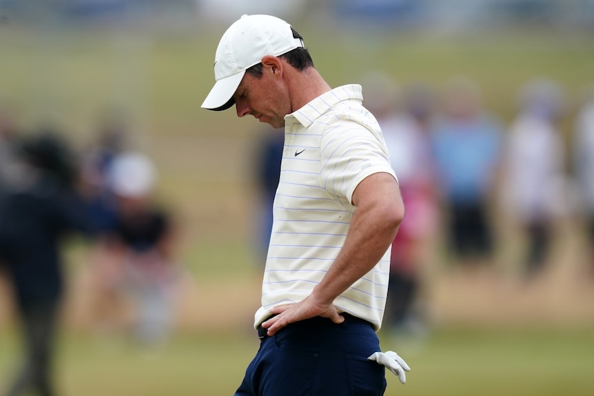 Rory McIlroy holds his hands on his hips and looks downwards