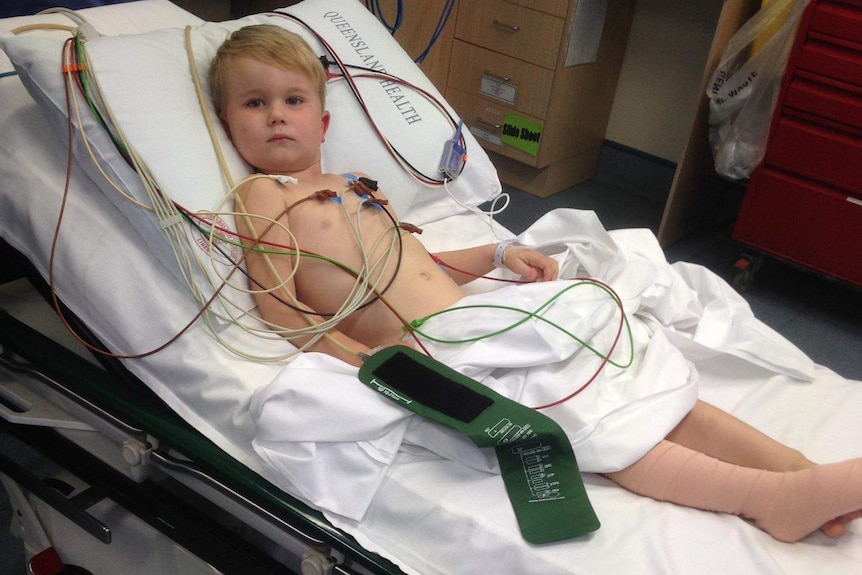 Four-year-old boy lying in hospital bed looking at camera, leg bandaged.