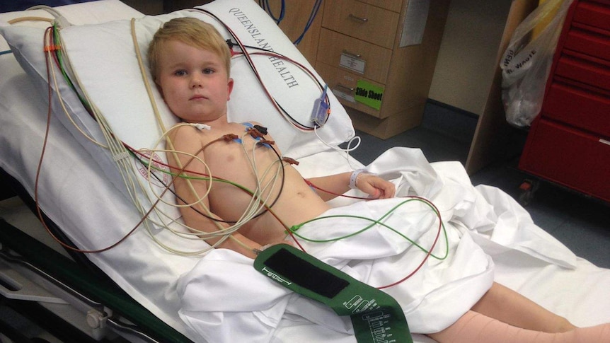 Four-year-old boy lying in hospital bed looking at camera, leg bandaged.