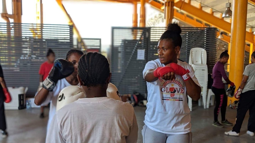 Debbie Kaore raises her hand to show how to punch as she watches to girls boxing.