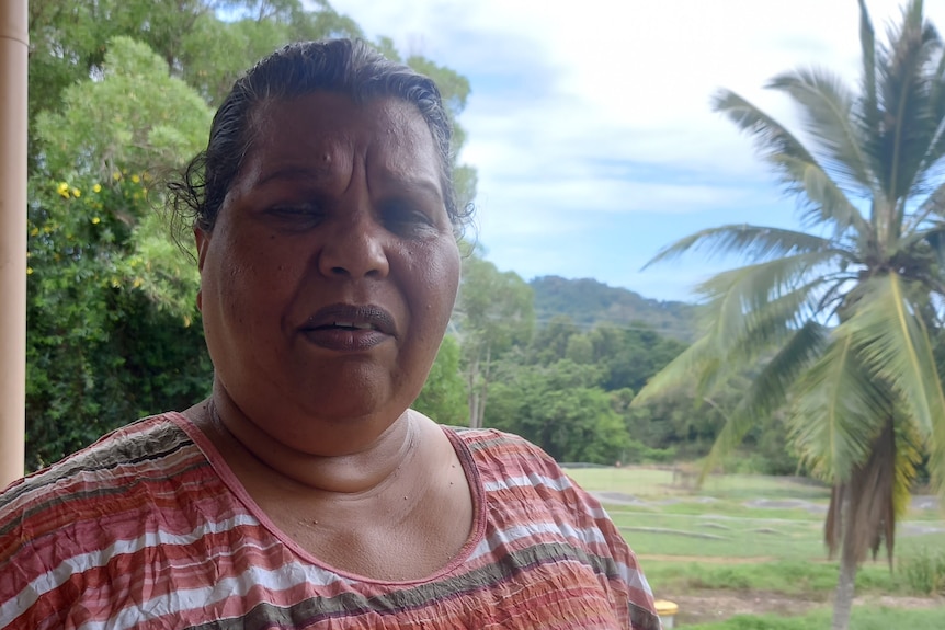 A woman with a red and white shirt standing in front of a tropical palm