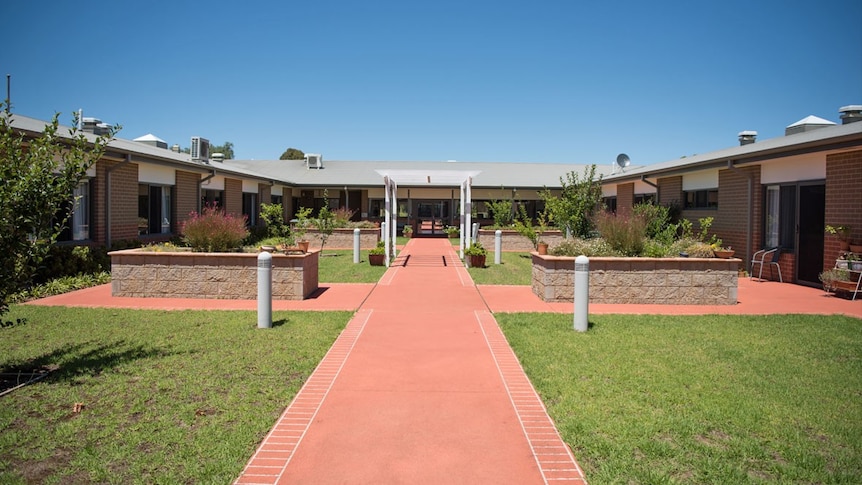 A red brick path leads to a U shaped building