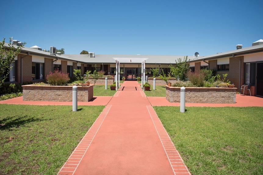 A red brick path leads to a U shaped building