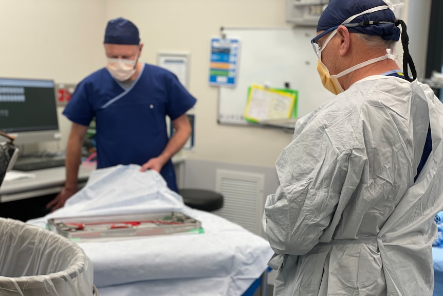 Deux médecins en blouse déballent un plateau de matériel médical stérilisé.