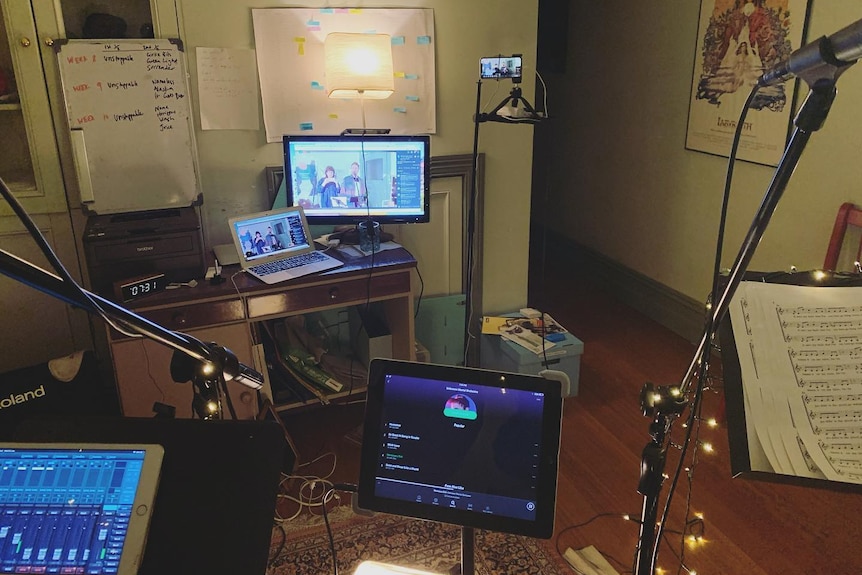 uma sala com muitos microfones e computadores configurados para um stream de vídeo online.