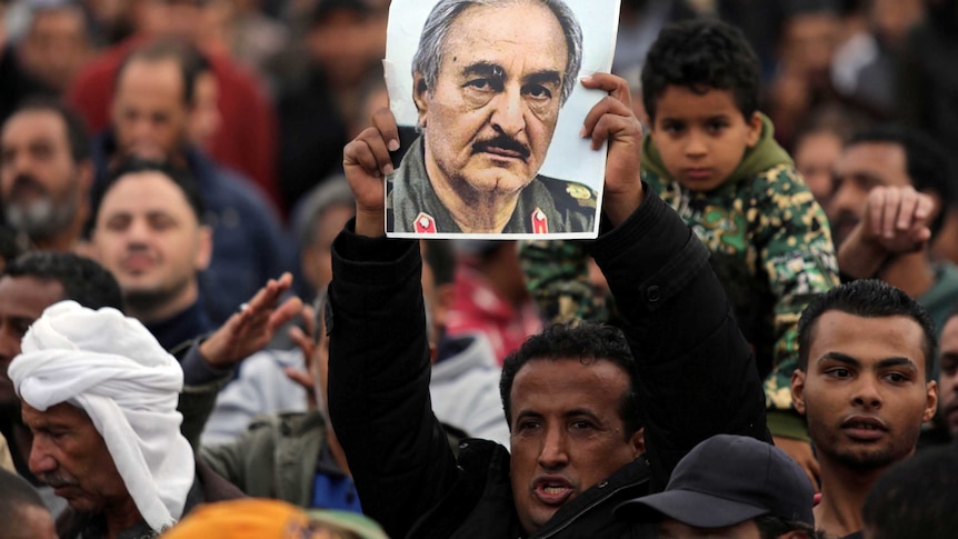 A man holds a poster of Eastern Libyan military commander Khalifa Haftar in a crowd of demonstrators.
