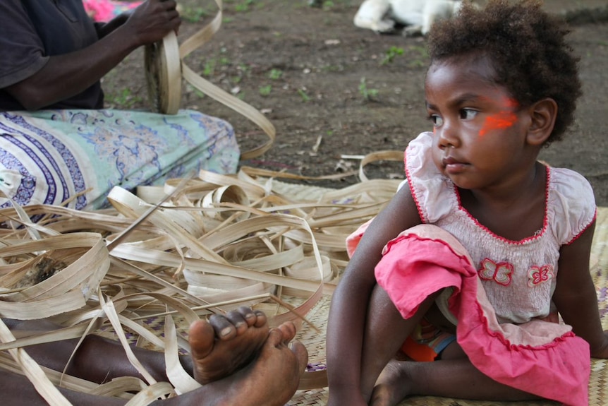 A baby girl sits on the floor in the village of Loutaliko, on Tanna in Vanuatu.