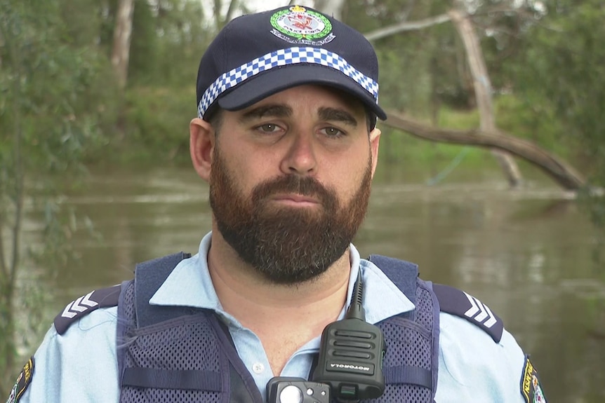 a man with a beard looking standing in front of a river