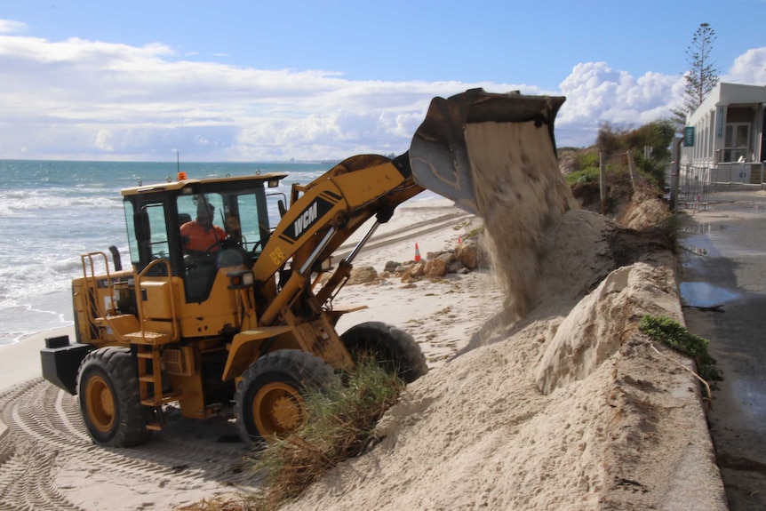 An excavator shores up sand on Port Beach after erosion from a storm.