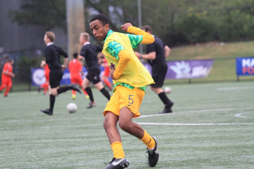 A football player running on the pitch with great effort.