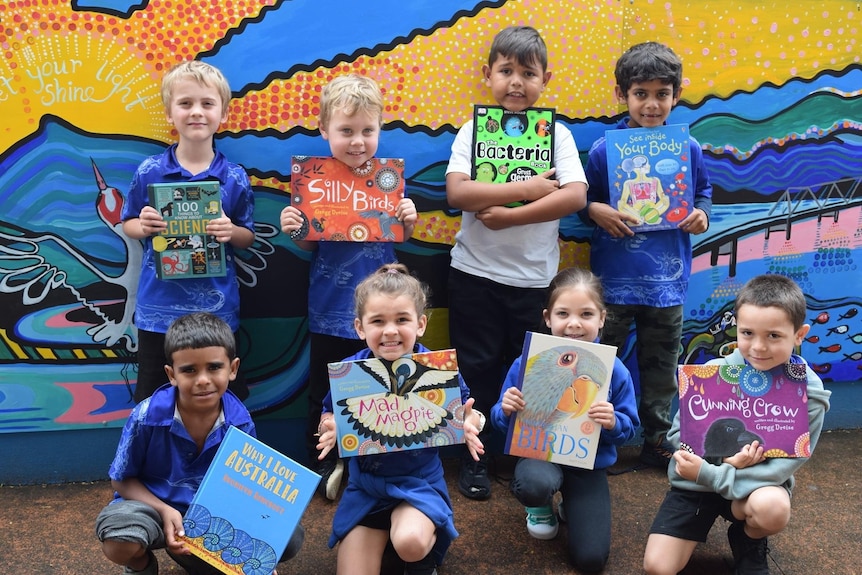 Primary school children hold up books donated by Corey Tutt