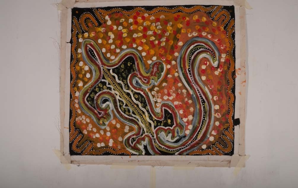 A red, black and brown painting of a goanna on canvas.