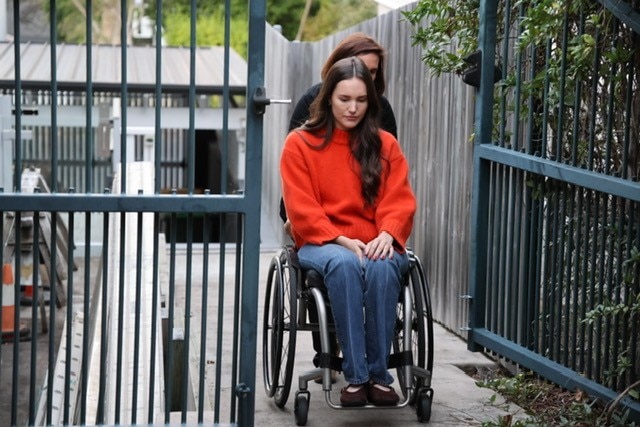 A woman pushes her daughter in a wheelchair.