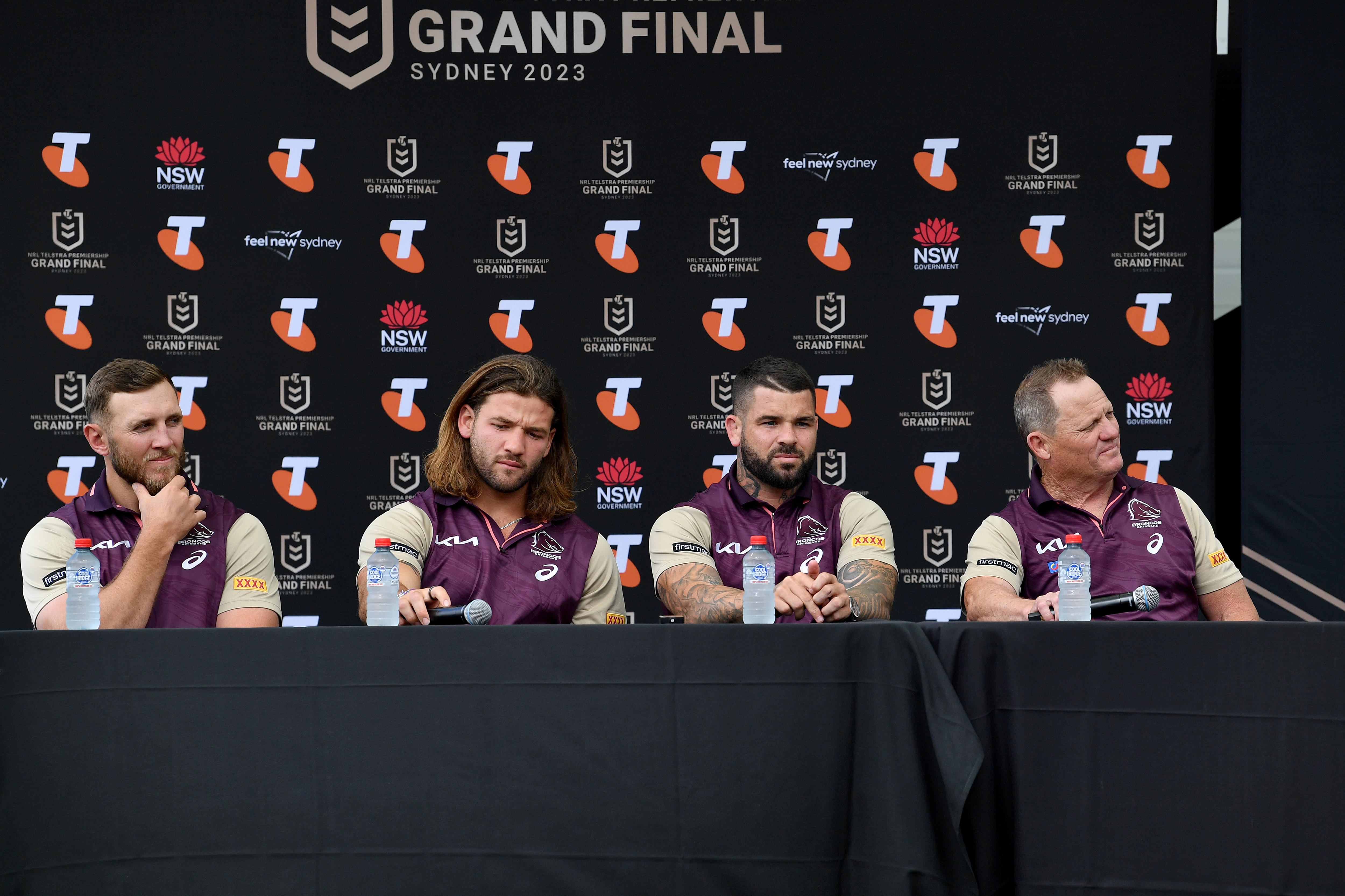 Four palyers and coach sit in front of media wall during a press conference in Broncos gear 