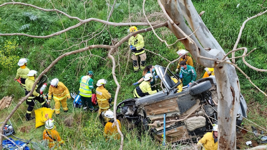 Emergency services surround an overturned car.