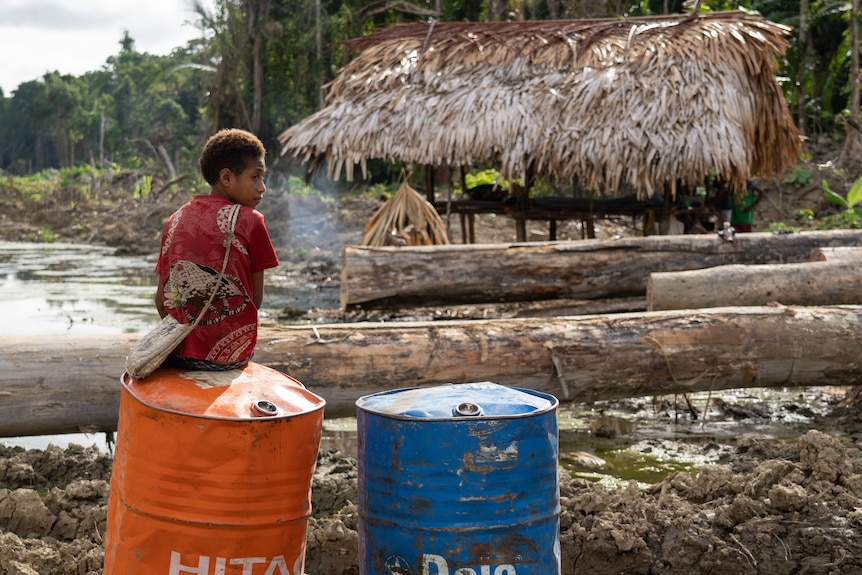 A child sits on a steel drum.