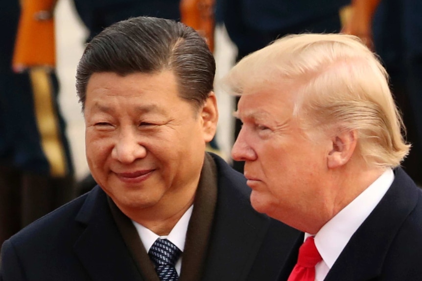 Xi Jinping smiles and Donald Turmp maintains a neutral expression as they look in front of where they stand.