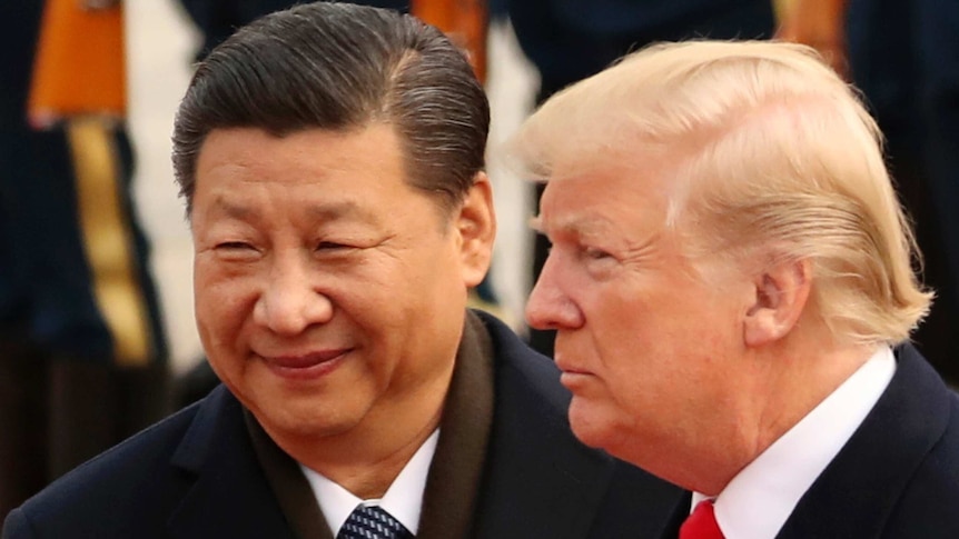 Xi Jinping smiles and Donald Turmp maintains a neutral expression as they look in front of where they stand.