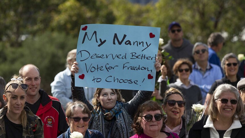 A young woman stands in a crowd of VAD supporters and her reads "My nanny deserved better, vote for freedom to choose!".