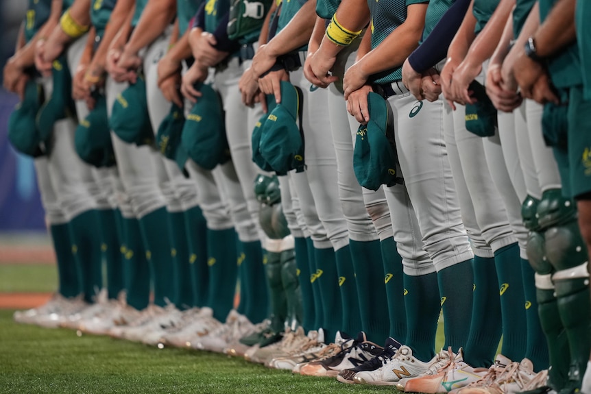 The Australian team lines up for the national anthem. Only their legs and hats, which the the players are holding, are visible