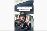 A woman does air quotes while sitting in the driver's seat of a car, with the subtitles "Dad: I think it's called 'ok boomer'"