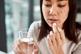 A woman takes an aspirin with a glass of water