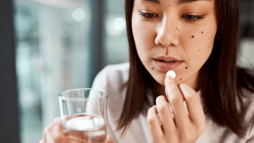 A woman takes an aspirin with a glass of water