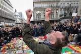 A man throws his fists in the air at a Brussels bombings memorial.