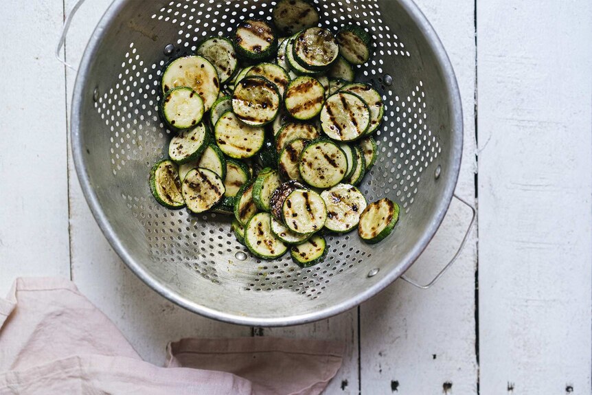 Sliced, chargrilled zucchini in a colander