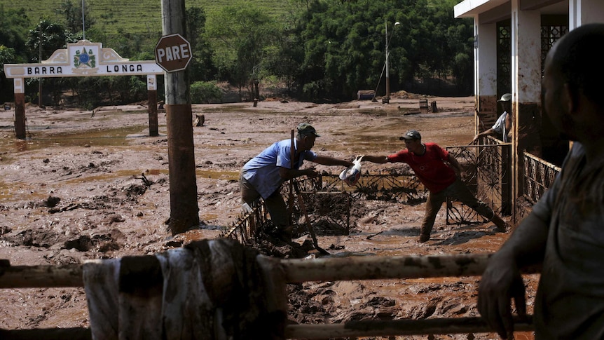 Men clean out a house flooded by mud