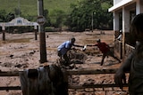 Men clean out a house flooded by mud