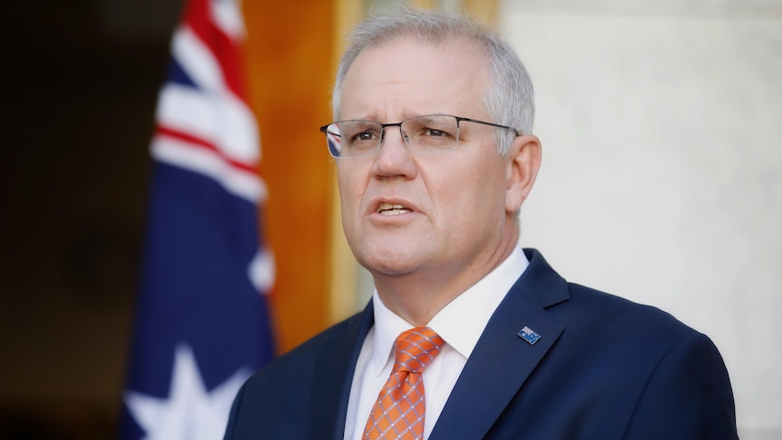 Morrison looks up in concentration as he's speaking at a press conference