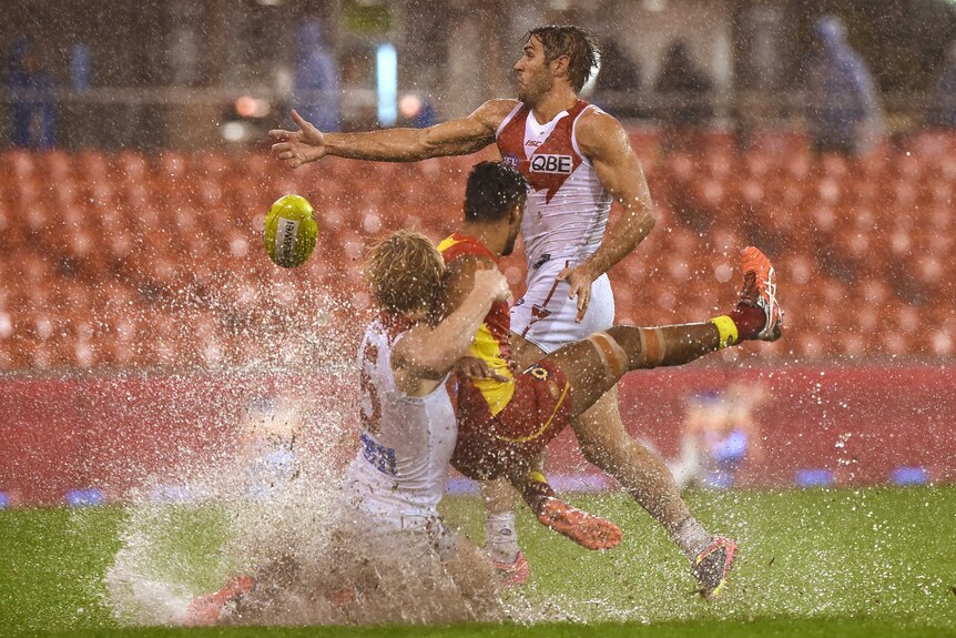 Sydney's Isaac Heeney (L) tackles Gold Coast's Aaron Hall in the wet at Carrara on June 4, 2016.