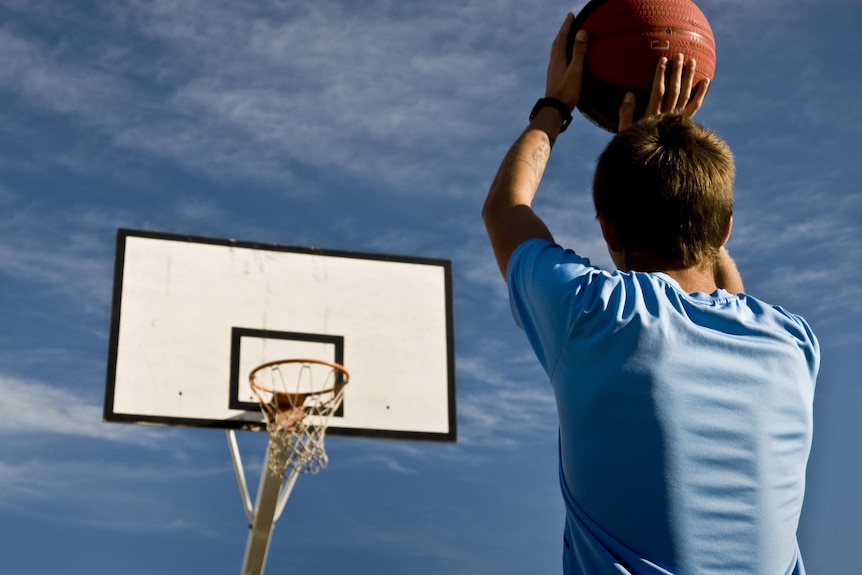 A young person prepares to throw a basketball towards a basketball hoop.